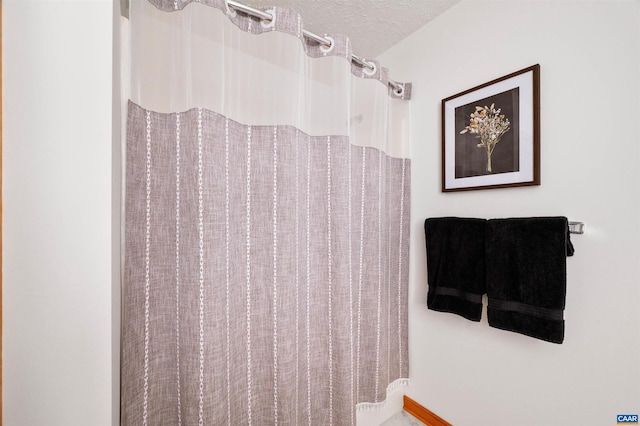 bathroom featuring curtained shower and a textured ceiling