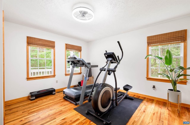 exercise area featuring wood finished floors, baseboards, and a textured ceiling