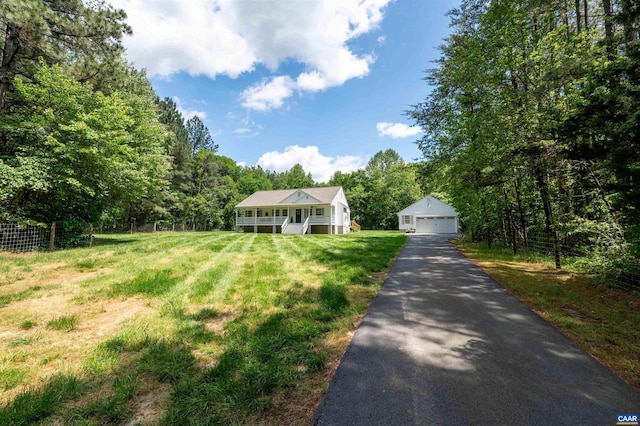 view of front facade featuring a detached garage, an outbuilding, a view of trees, and covered porch