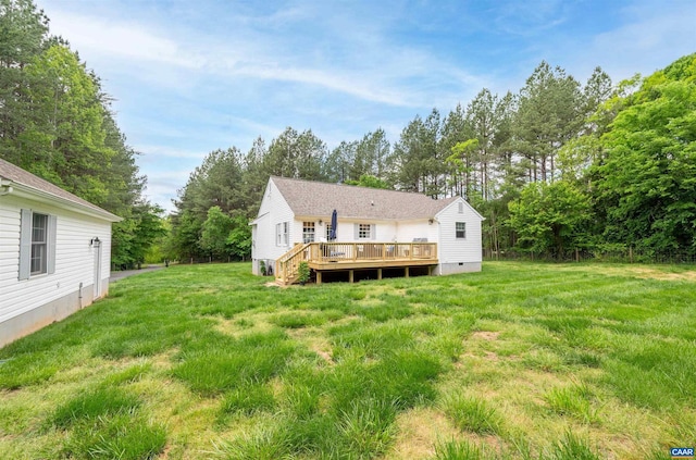 back of property featuring a deck, crawl space, a yard, and view of wooded area