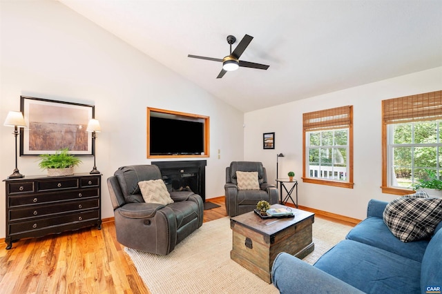 living area featuring vaulted ceiling, light wood finished floors, a ceiling fan, and baseboards