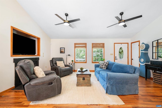 living area with a ceiling fan, vaulted ceiling, wood finished floors, and baseboards