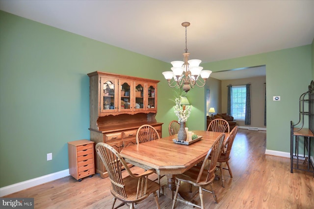 dining area featuring a chandelier, baseboards, and light wood-style floors