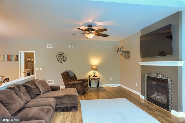 living area featuring wood finished floors, ceiling fan, and a tile fireplace