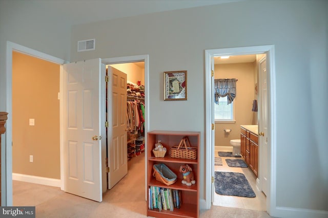 bedroom with a spacious closet, a closet, baseboards, and ensuite bathroom