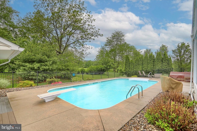 view of pool featuring a patio area, a diving board, a fenced backyard, and view of scattered trees