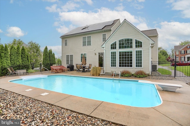 view of pool with fence, a patio, and a diving board