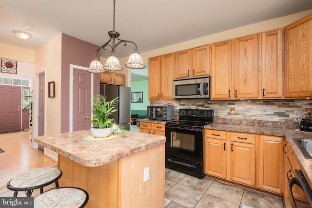 kitchen with black appliances, backsplash, a center island, and a breakfast bar