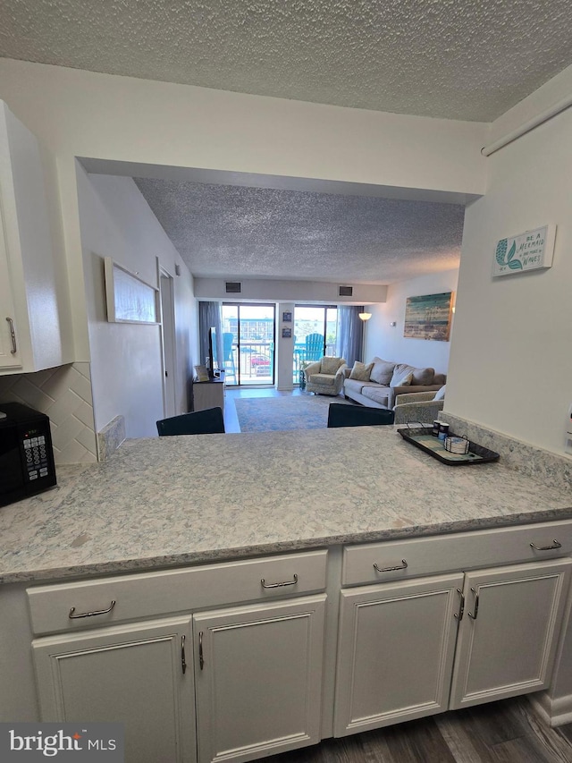 13100 Coastal Hwy Unit 1110, Ocean City, MD 21842 - kitchen with a textured ceiling, black microwave, light countertops, white cabinets, and open floor plan