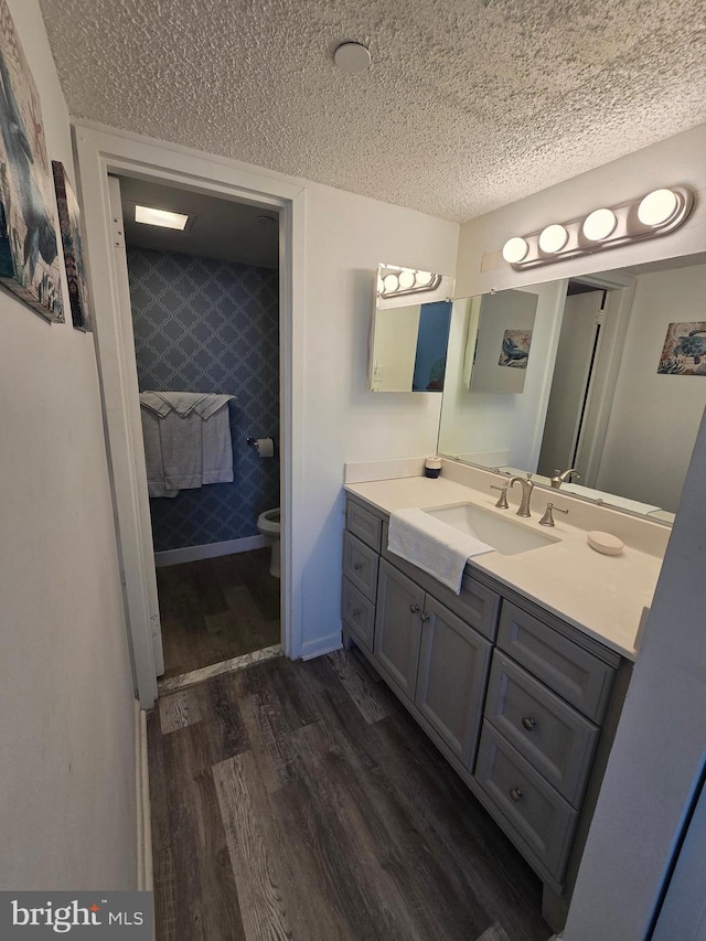 13100 Coastal Hwy Unit 1110, Ocean City, MD 21842 - bathroom with wood finished floors, a textured ceiling, toilet, vanity, and wallpapered walls