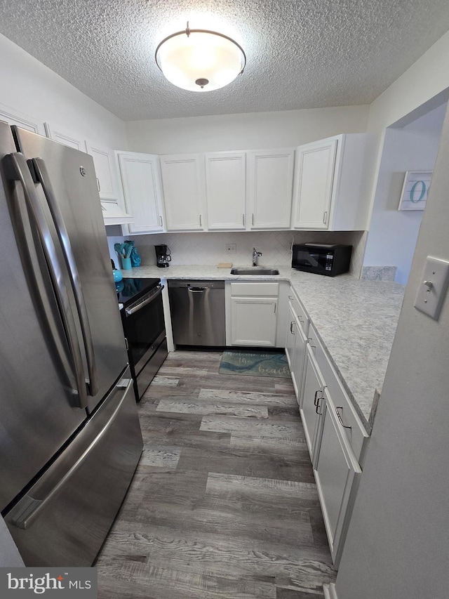 13100 Coastal Hwy Unit 1110, Ocean City, MD 21842 - kitchen featuring stainless steel appliances, a sink, dark wood-type flooring, a textured ceiling, and white cabinets