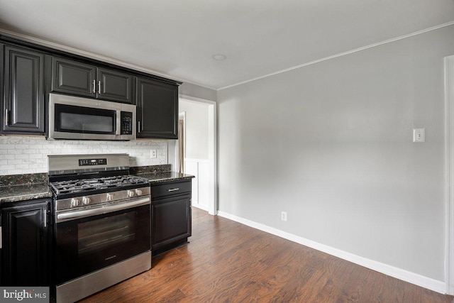 kitchen with stainless steel appliances, dark cabinetry, decorative backsplash, baseboards, and crown molding