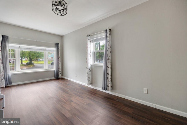 unfurnished room with wood finished floors, healthy amount of natural light, and baseboards