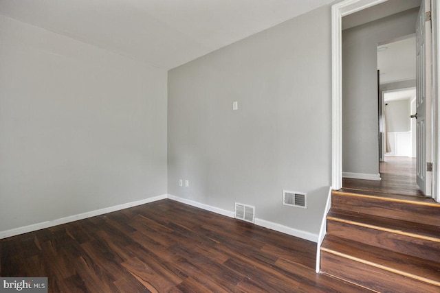 spare room featuring baseboards and dark wood finished floors