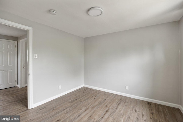 unfurnished room featuring wood finished floors, baseboards, and a smoke detector