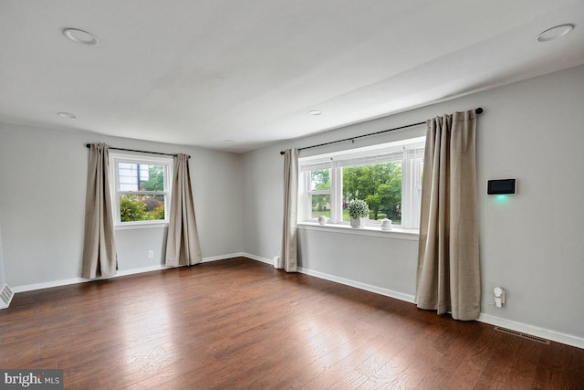 empty room featuring wood finished floors, baseboards, and recessed lighting