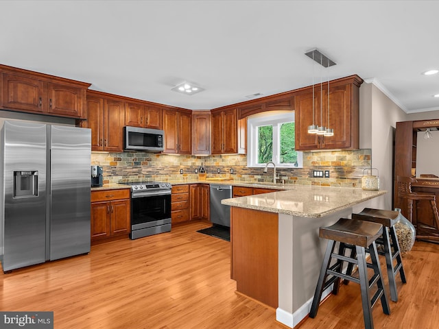 2039 Choptank Ave, Pasadena, MD 21122 - kitchen with stainless steel appliances, a peninsula, light stone counters, light wood-style floors, and crown molding