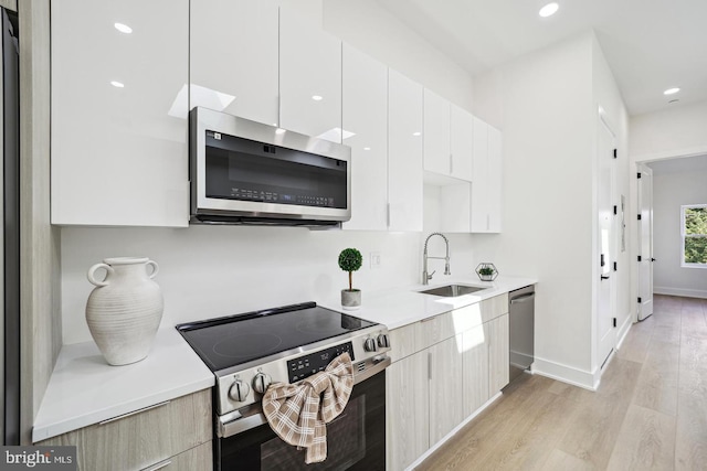 705 Quincy St NE Unit 5D, Washington, DC 20017 - kitchen with stainless steel appliances, a sink, modern cabinets, light wood-style flooring, and light countertops