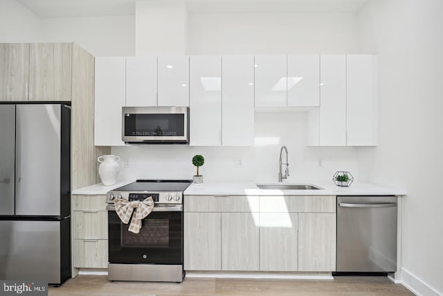 705 Quincy St NE Unit 5D, Washington, DC 20017 - kitchen with appliances with stainless steel finishes, a sink, modern cabinets, light countertops, and light wood-type flooring