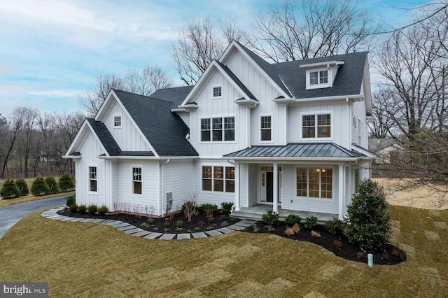 modern farmhouse featuring covered porch, board and batten siding, roof with shingles, and a front lawn