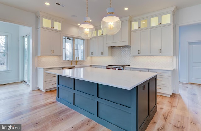 kitchen featuring white cabinets, a center island, decorative backsplash, light wood-style floors, and recessed lighting