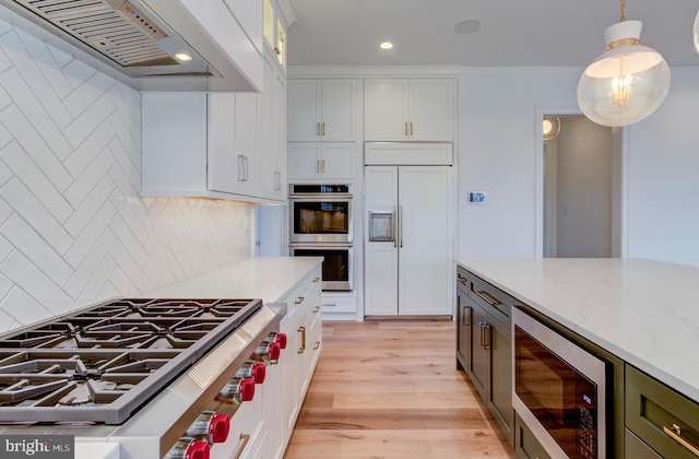 kitchen featuring built in appliances, premium range hood, light wood-type flooring, recessed lighting, and backsplash