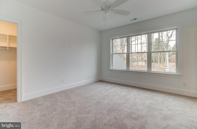 unfurnished bedroom featuring a spacious closet, light carpet, multiple windows, and baseboards