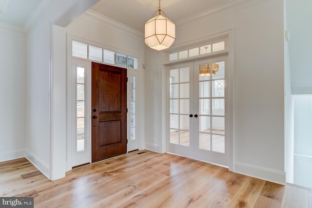 entrance foyer with french doors, light wood-type flooring, crown molding, and baseboards