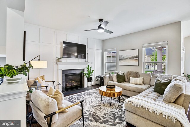living room with ceiling fan, a fireplace with flush hearth, and wood finished floors