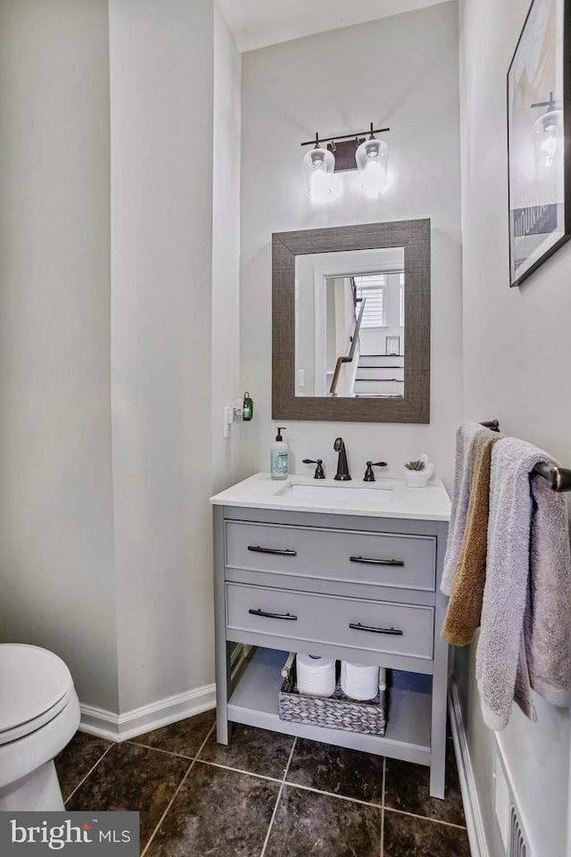 half bathroom with vanity, toilet, baseboards, and tile patterned flooring