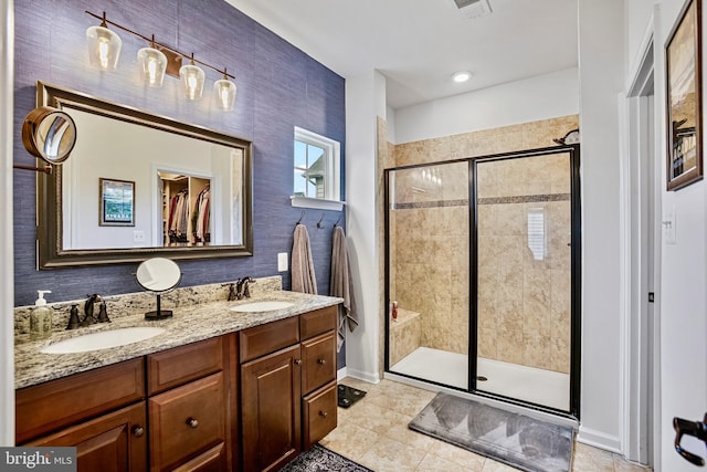bathroom with a shower stall, tile patterned flooring, double vanity, and baseboards