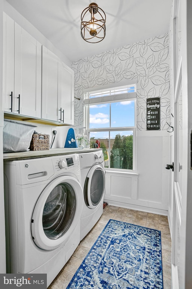 washroom featuring independent washer and dryer, cabinet space, wallpapered walls, and light tile patterned flooring