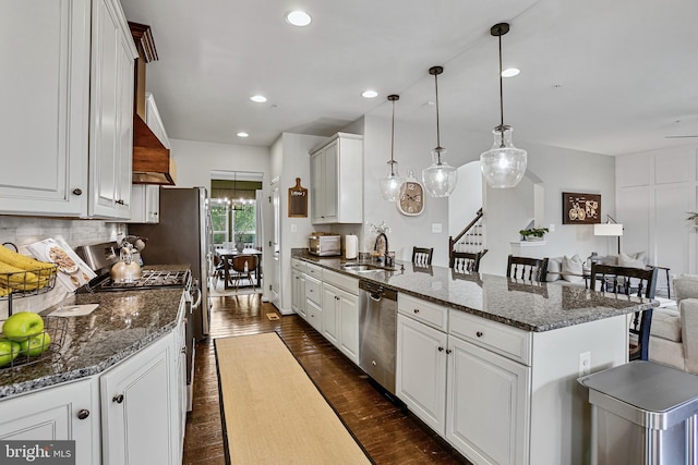 kitchen featuring appliances with stainless steel finishes, a sink, a peninsula, white cabinetry, and recessed lighting