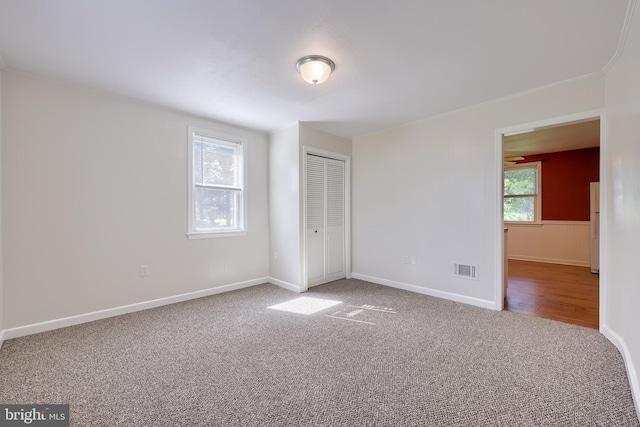 unfurnished bedroom with carpet floors, a closet, freestanding refrigerator, and baseboards