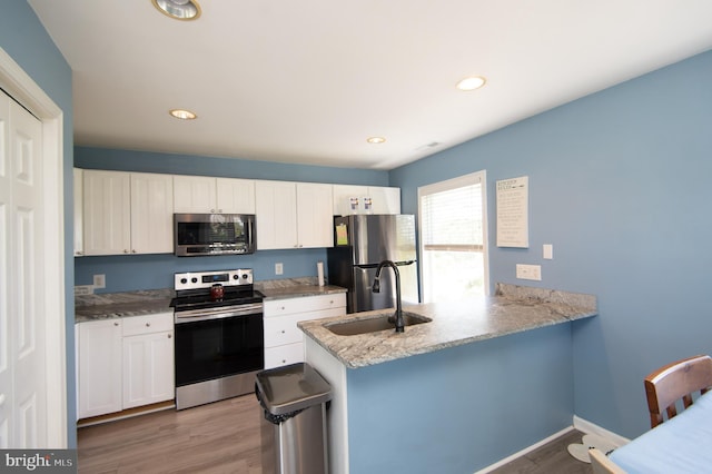 4906 Timbermarsh Ln, Woolford, MD 21677 - kitchen with appliances with stainless steel finishes, a sink, a peninsula, wood finished floors, and white cabinetry
