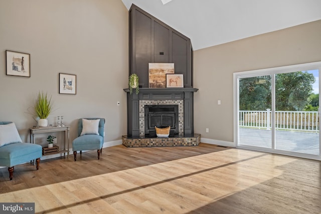 living area with high vaulted ceiling, wood finished floors, a fireplace, and baseboards