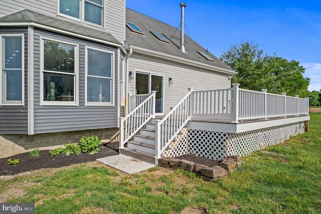 back of property featuring a deck, a lawn, and a shingled roof