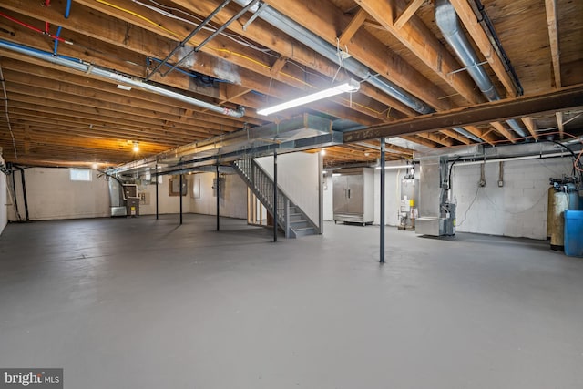 unfinished below grade area featuring water heater, stairway, heating unit, and a water softener