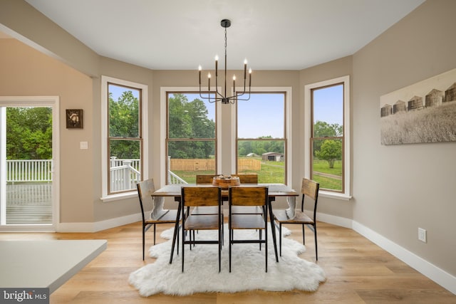 dining room featuring baseboards, a chandelier, and light wood finished floors