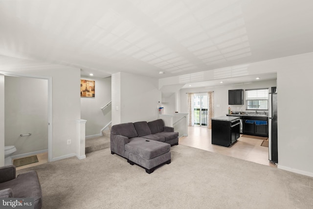 living room featuring stairs, light carpet, and baseboards