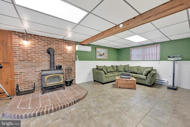 191 Meadow Dr, Mohrsville, PA 19541 - tiled living room with a wall mounted air conditioner, a wood stove, baseboard heating, a paneled ceiling, and wainscoting
