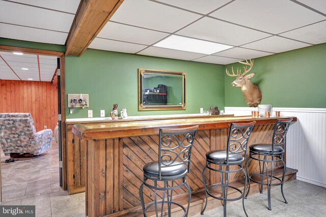 191 Meadow Dr, Mohrsville, PA 19541 - indoor wet bar with wood walls, wainscoting, a paneled ceiling, and tile patterned flooring