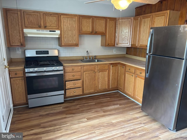kitchen featuring appliances with stainless steel finishes, under cabinet range hood, a sink, and light countertops