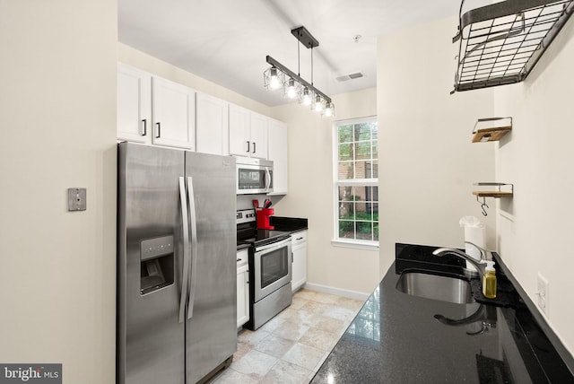 42432 Hollyhock Ter Unit 101, Brambleton, VA 20148 - kitchen with appliances with stainless steel finishes, a sink, white cabinetry, dark stone counters, and hanging light fixtures