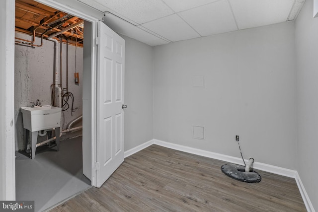 basement with wood finished floors, baseboards, and a sink