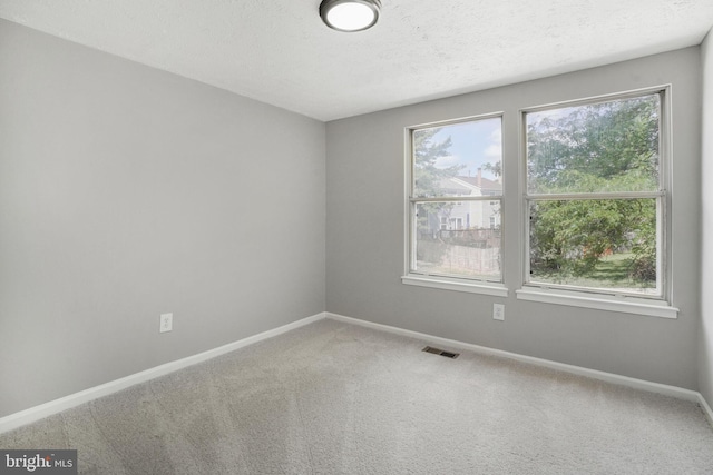 carpeted empty room with baseboards and a textured ceiling