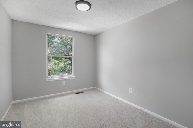 carpeted empty room featuring a textured ceiling and baseboards