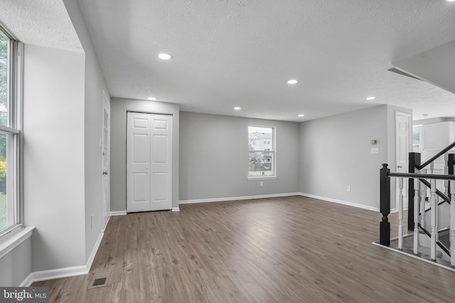 below grade area with a textured ceiling, wood finished floors, baseboards, and recessed lighting