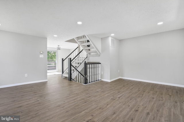 spare room with wood finished floors, stairway, recessed lighting, baseboards, and a textured ceiling