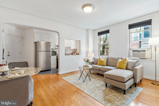 living area with light wood-style flooring, cooling unit, and baseboards